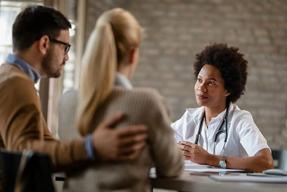 Médico em consulta com um casal em uma clínica